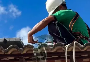 Profissional instalando tela de proteção em telhado para manejo de pombos